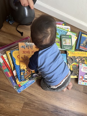 Baby crawling on books sprawled on the floor.